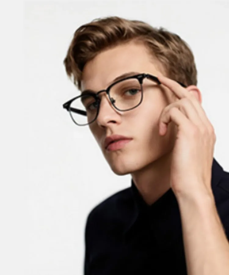 眼鏡をかけた男性のポートレート。男性は黒いフレームの眼鏡をかけており、指で眼鏡に触れている。