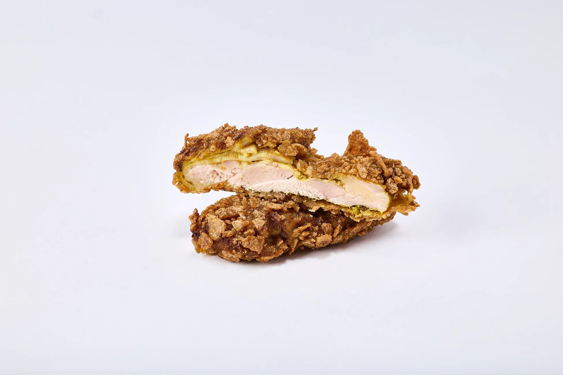 揚げられた鶏肉が半分にカットされた写真。鶏肉は衣で覆われており、内部の肉が見えています。