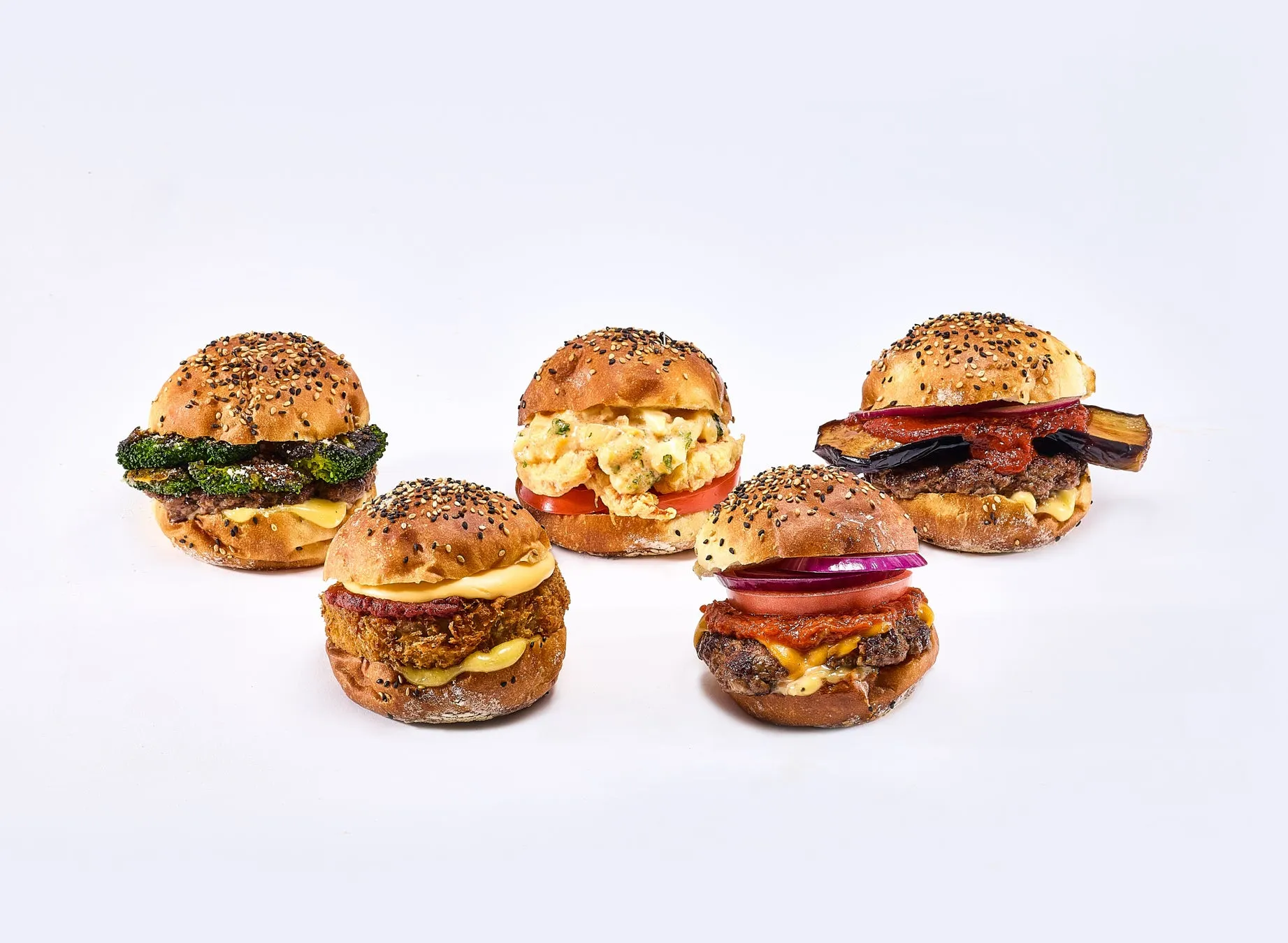 様々なハンバーガーが白背景に並んでいる写真です。ハンバーガーは、ブロッコリー、卵サラダ、ナス、赤玉ねぎ、トマトなど、様々な具材が使われています。