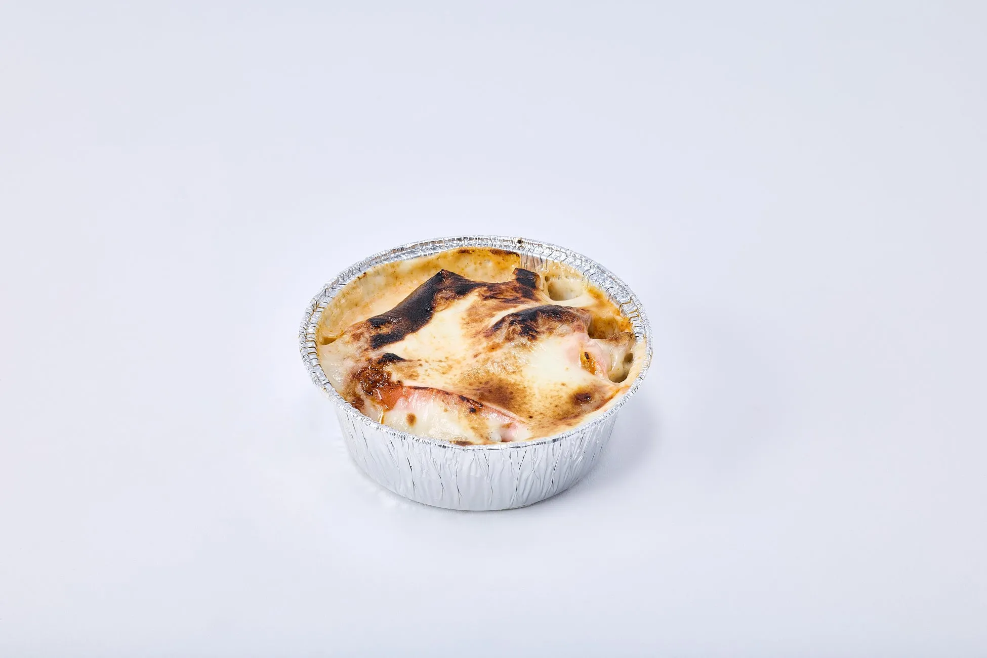 アルミカップに入った、表面が焦げ目のついた料理の写真です。