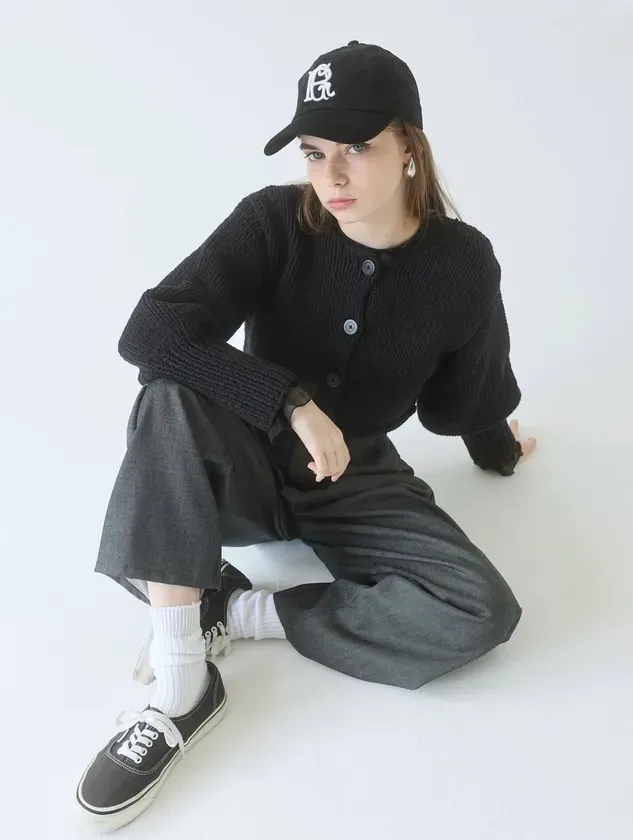 黒い帽子とカーディガンを着て床に座っている女性