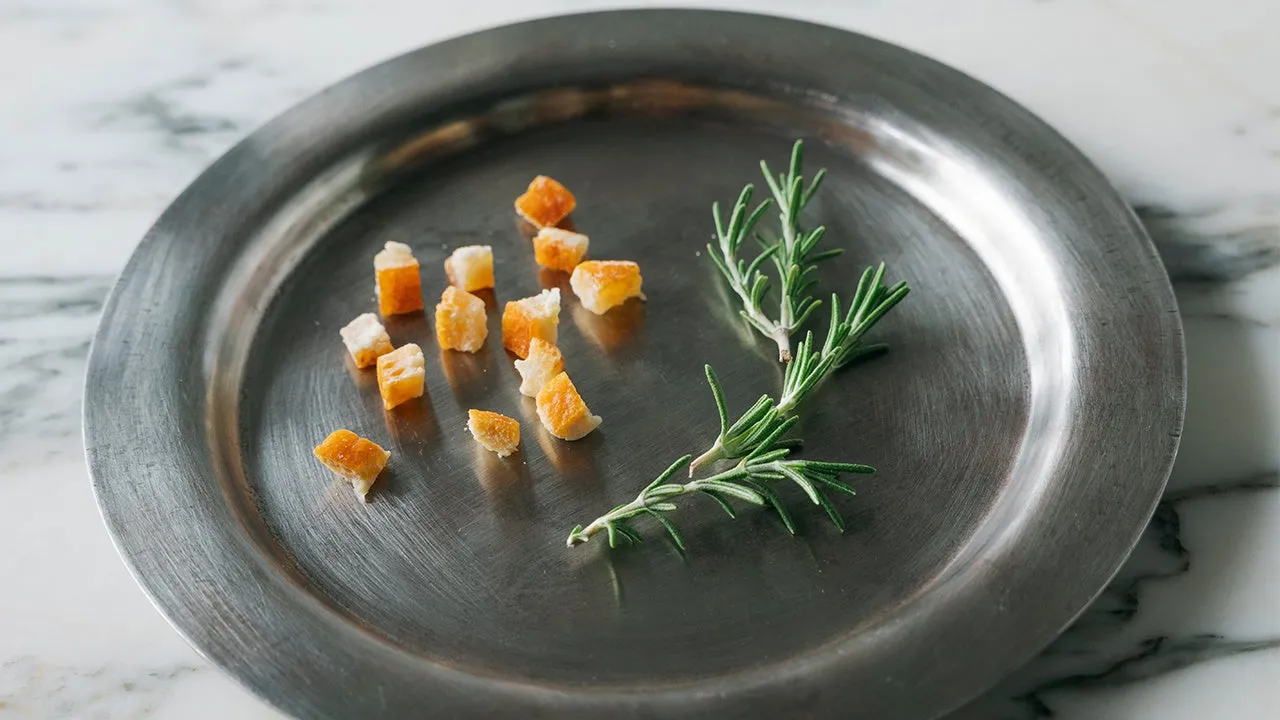 銀色の皿の上に、パンの立方体とローズマリーの小枝が置かれています。