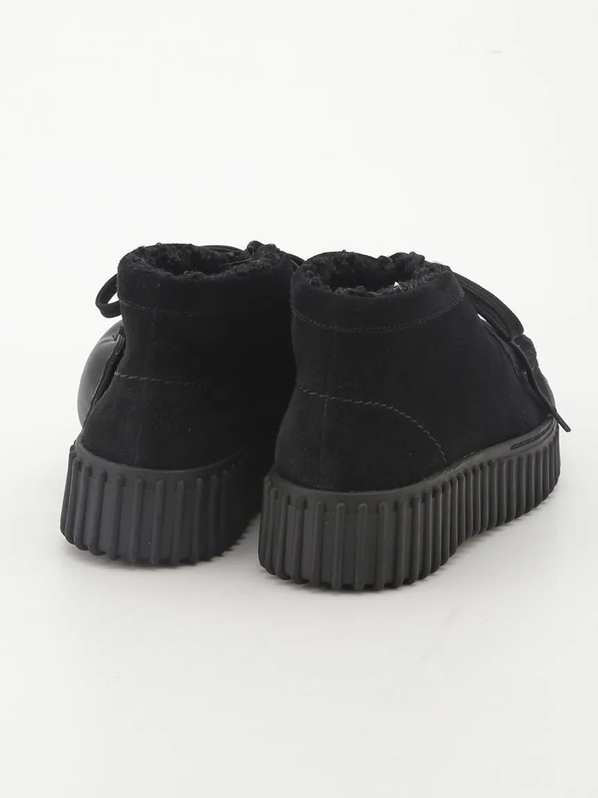 黒いプラットフォームブーツのクローズアップ写真。ブーツはスエードのような素材で作られており、厚いプラットフォームソールが付いている。