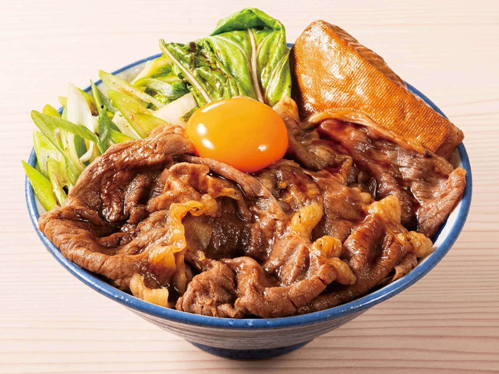 牛肉、卵、野菜が盛り付けられた丼のクローズアップ。