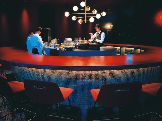 バーカウンターでカクテルを作るバーテンダー