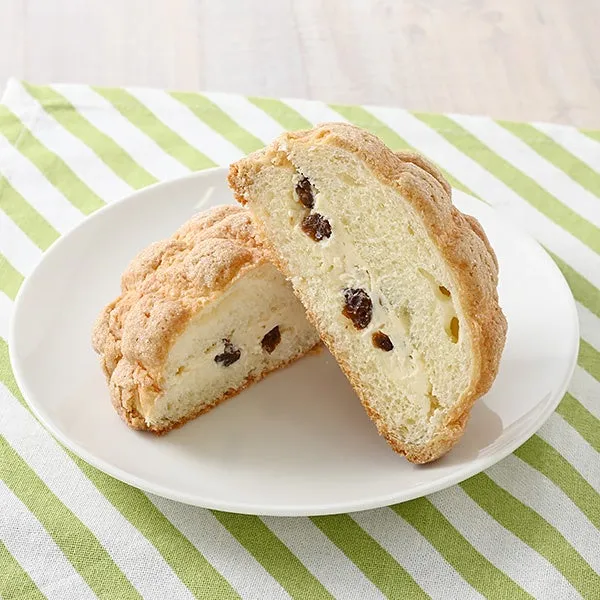 白い皿に載った、レーズンが入ったパンの断面図。パンは2つにカットされており、クリームチーズのような白いフィリングが詰められている。