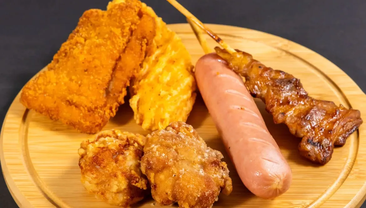 木製の皿に揚げ物やソーセージ、焼き鳥が乗せられた写真です。