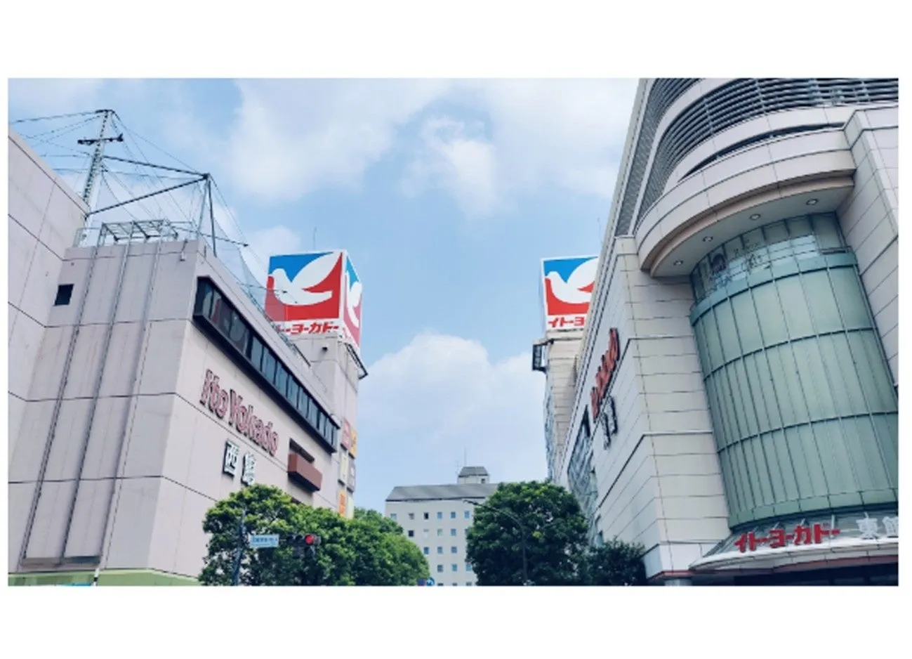 空の下、2つのイトーヨーカドーの建物が並んで立っている写真です。それぞれの建物の上には、イトーヨーカドーのロゴマークが掲げられています。