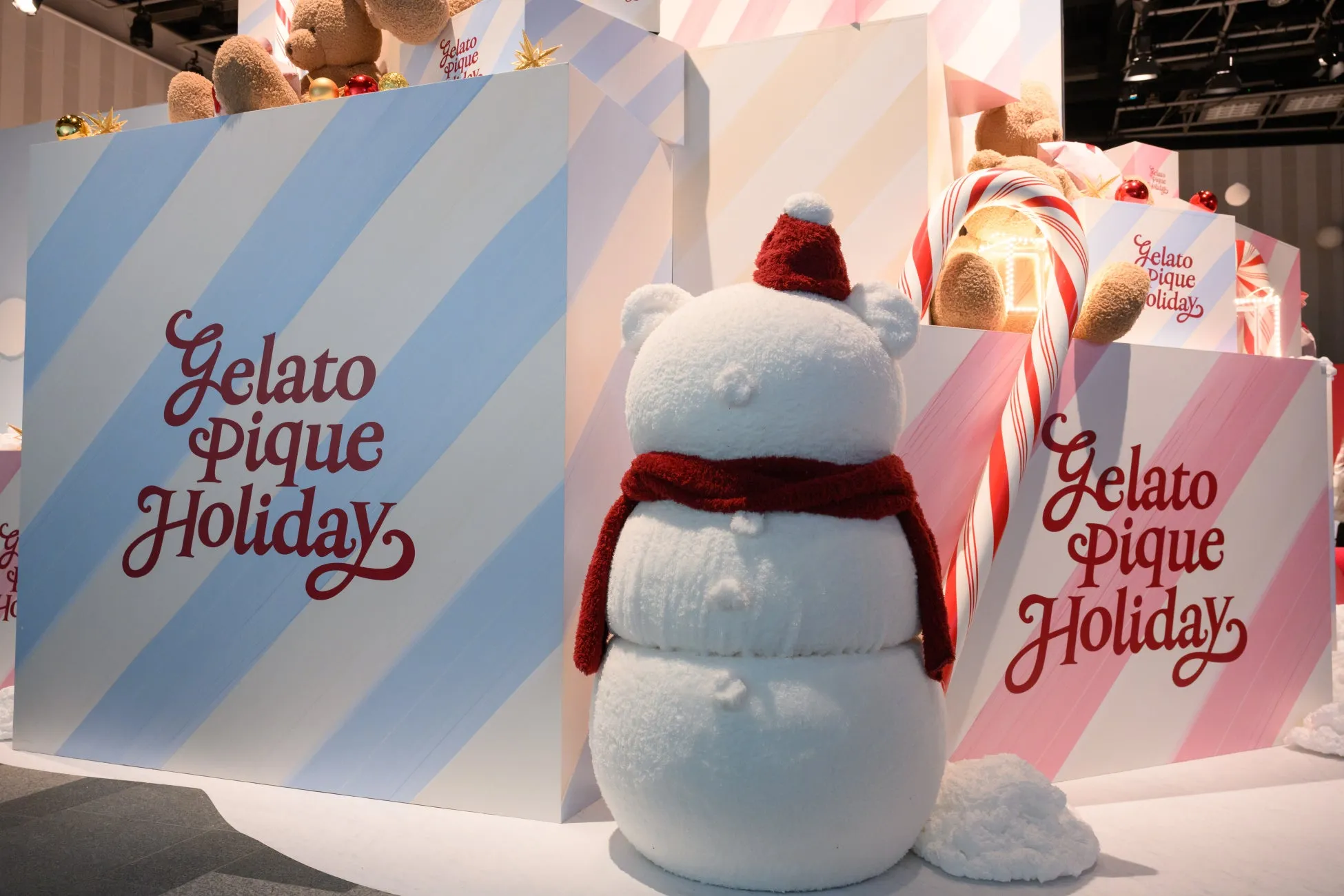 雪だるまのオブジェと、クリスマスをテーマにしたディスプレイ。背景には、ストライプ模様の壁や、テディベアの人形、キャンディケインなどが配置されている。