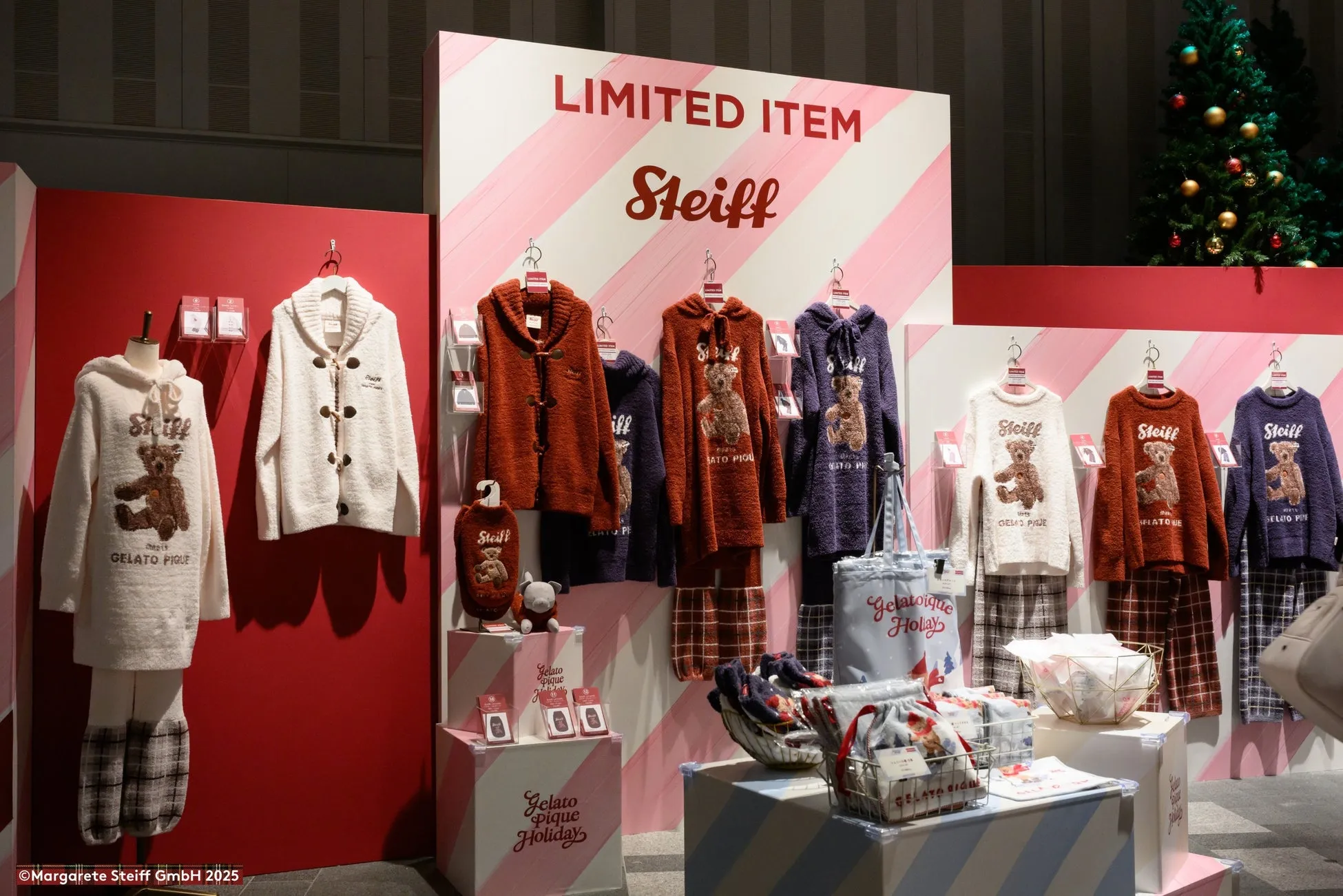 Steiffのテディベアがデザインされたアパレルが並ぶ、クリスマスをテーマにした展示の様子。限定アイテムやギフトセットが販売されている。