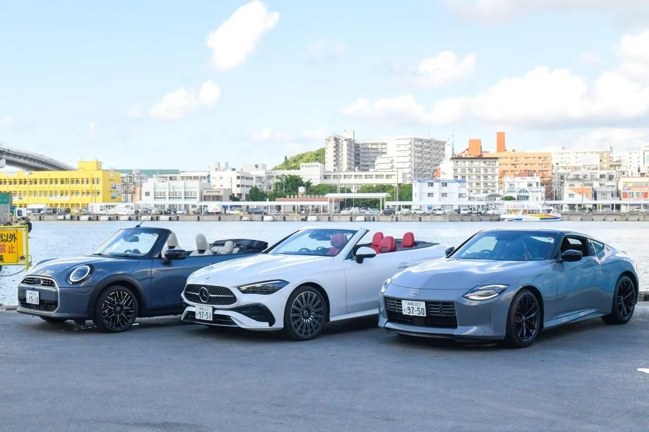 3台のオープンカーが並んだ写真。左から、青いMINI、白いMercedes-Benz、グレーのNissan Z。背景には建物と海が見える。