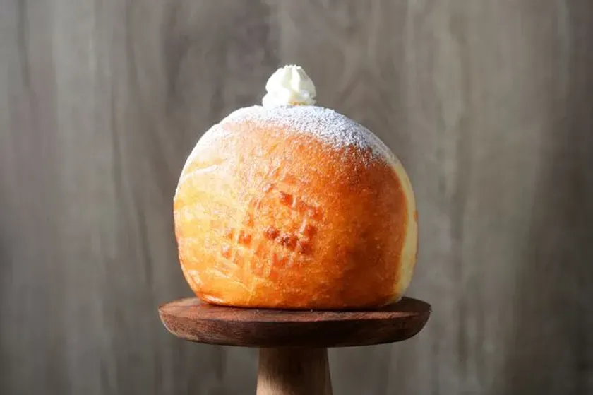 粉砂糖がまぶされた丸いパン。ホイップクリーム