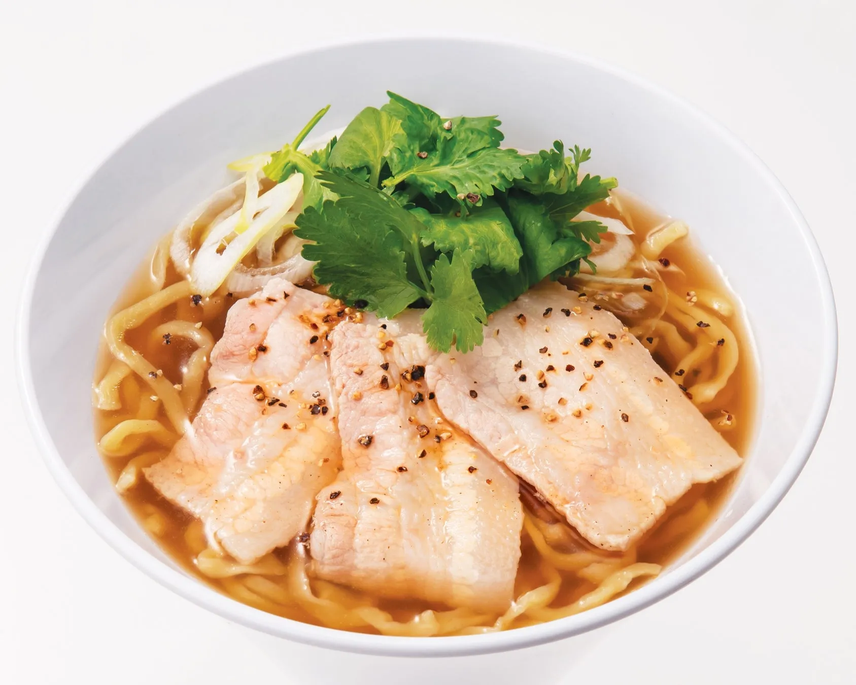 白い器に入ったラーメンの写真です。麺、チャーシュー、ネギ、パクチーが具材として使われています。