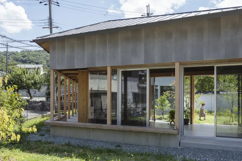 木材とコンクリートで作られたモダンな日本の家。 屋根が低く、窓が大きく、屋外とのつながりが感じられる。