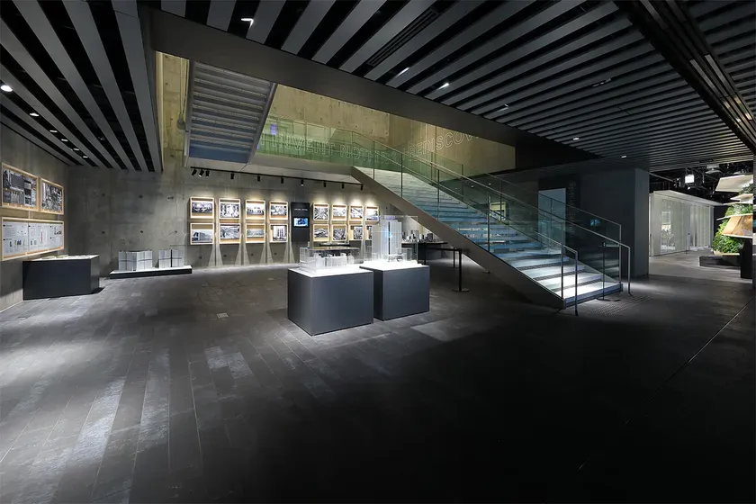 展示スペースのインテリア写真。階段、模型、写真が展示されており、スタイリッシュな雰囲気。