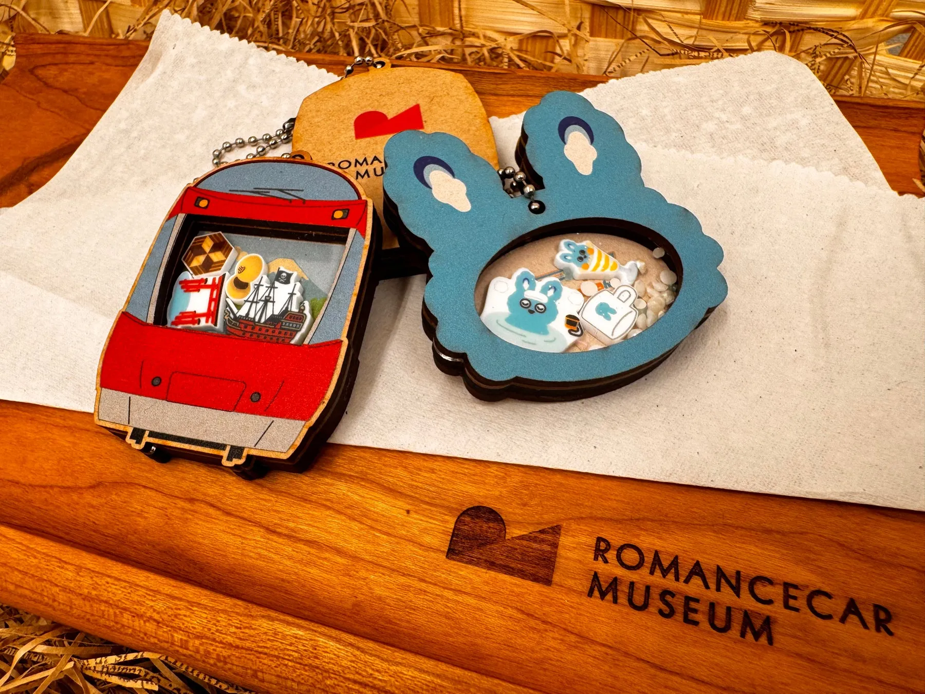 木製のキーホルダー。赤い電車、茶色のタグ、青いウサギの形。