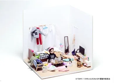 リカちゃんの人形が部屋でくつろいでいる様子を描いたミニチュア写真。ベッド、化粧台、テレビなどがあり、洋服が壁にかけられている。