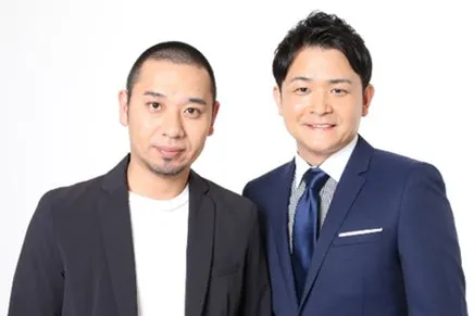 2人の男性が写った写真。2人ともスーツを着ており、カメラ目線で微笑んでいる。
