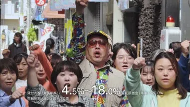 群衆の中で拳を突き上げ、訴えるように口を開けている男性を中心に、周囲の人々も拳を突き上げている様子。