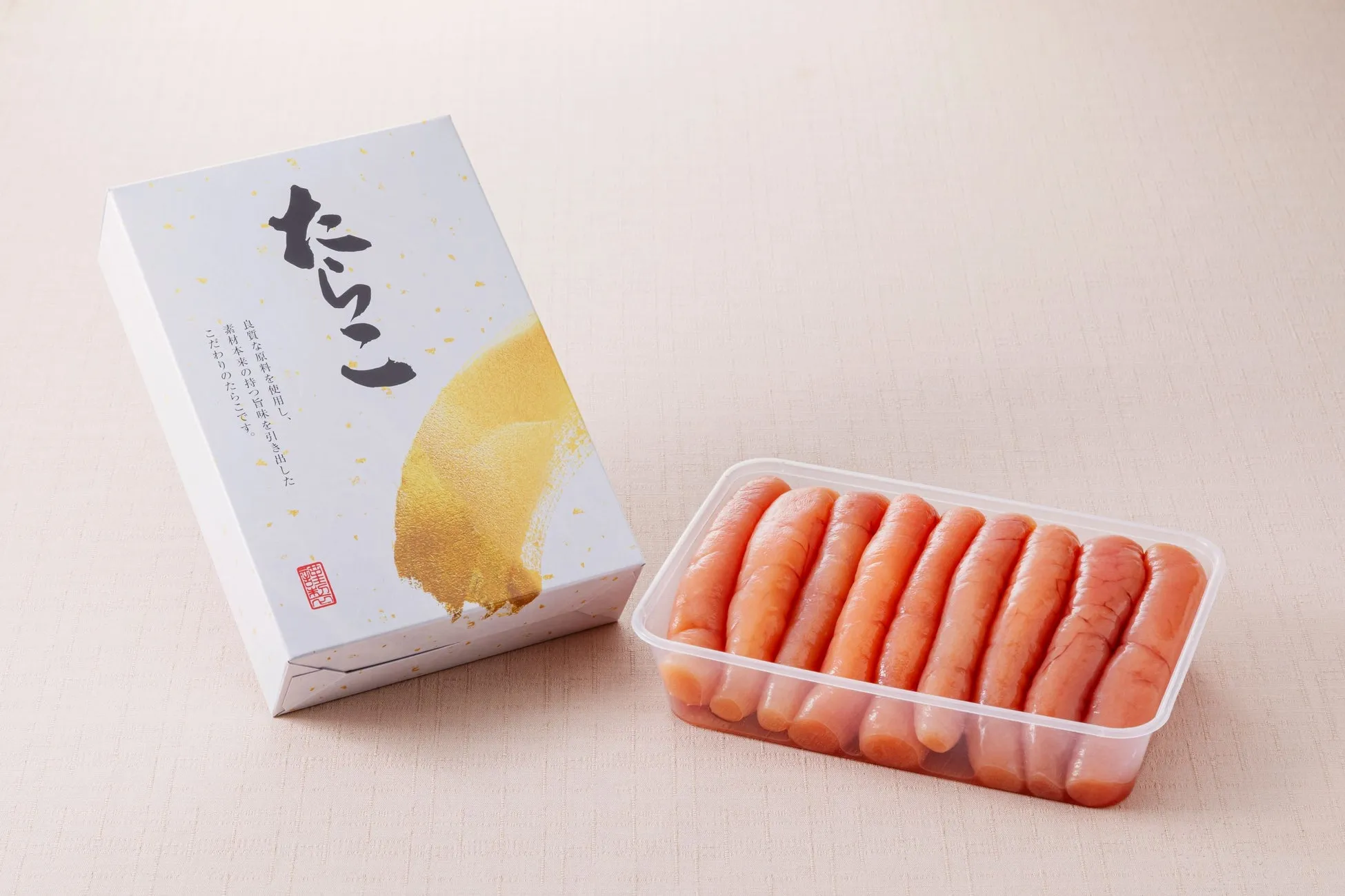 白い箱と、たらこが透明なプラスチック容器に入っている写真。箱には「たらこ」の文字と、金色の装飾が施されている。