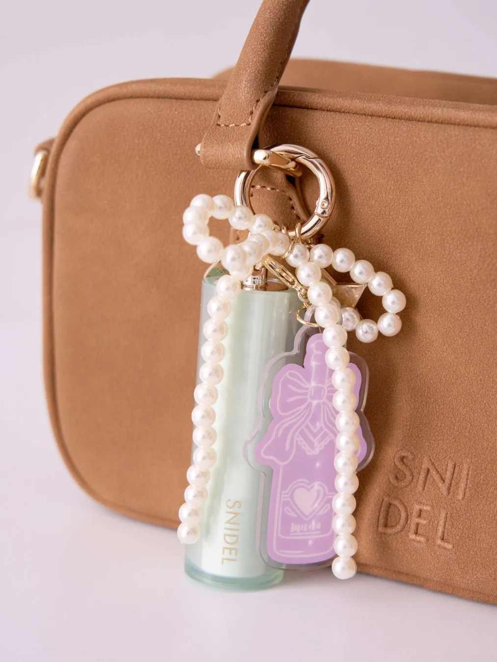 茶色のバッグに、パールチェーンと香水瓶のチャームが付いている。チャームには「SNIDEL」の文字が書かれている。