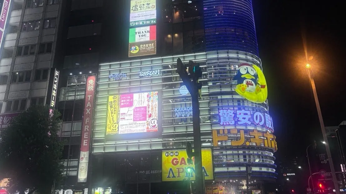 夜の街並みの写真。ドン・キホーテの看板が目立ち、周囲には様々な店舗の看板が並んでいる。