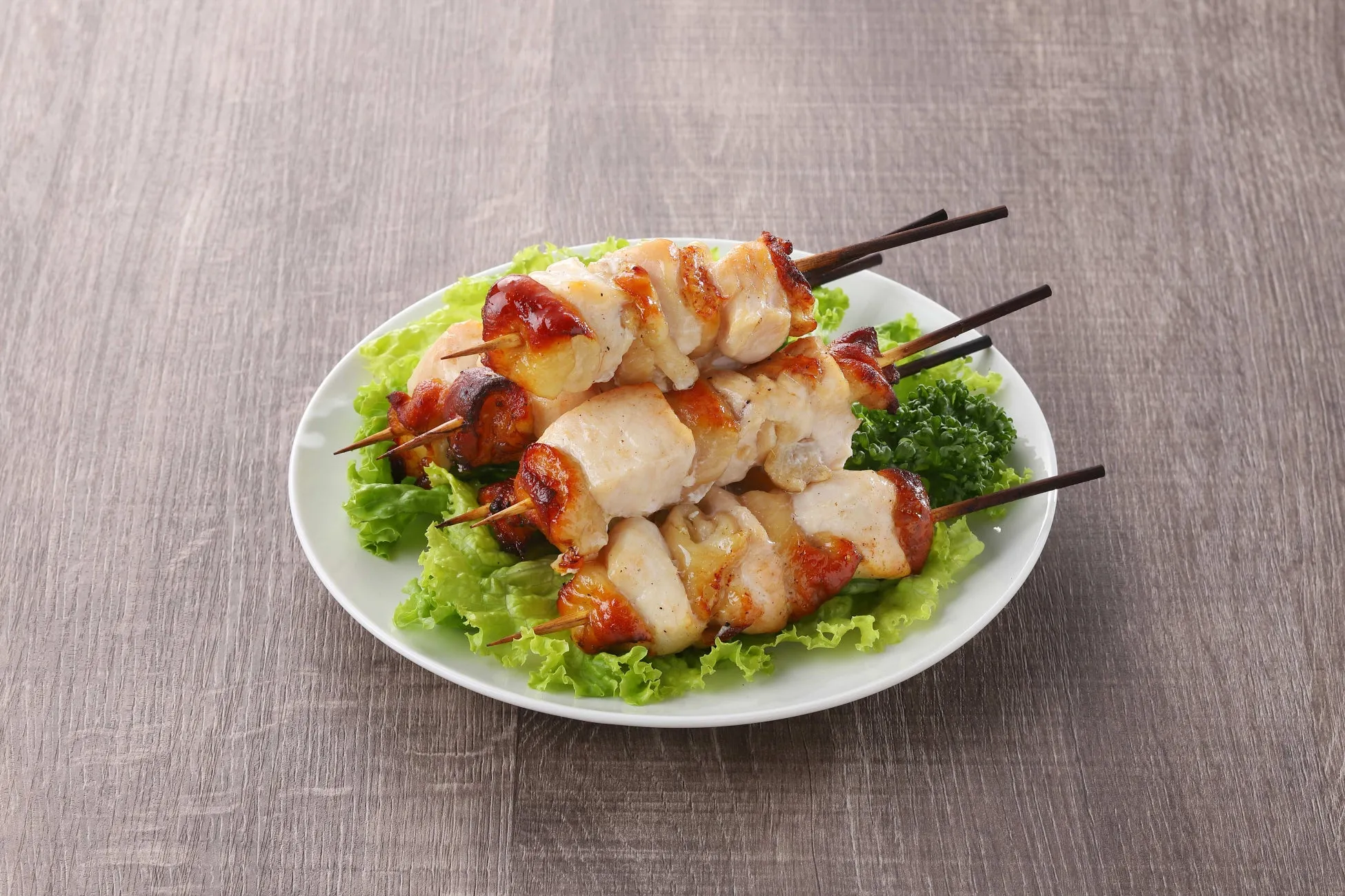 お皿に盛られた鶏肉の串焼きの写真です。鶏肉は焼き色がついており、レタスの上に盛り付けられています。