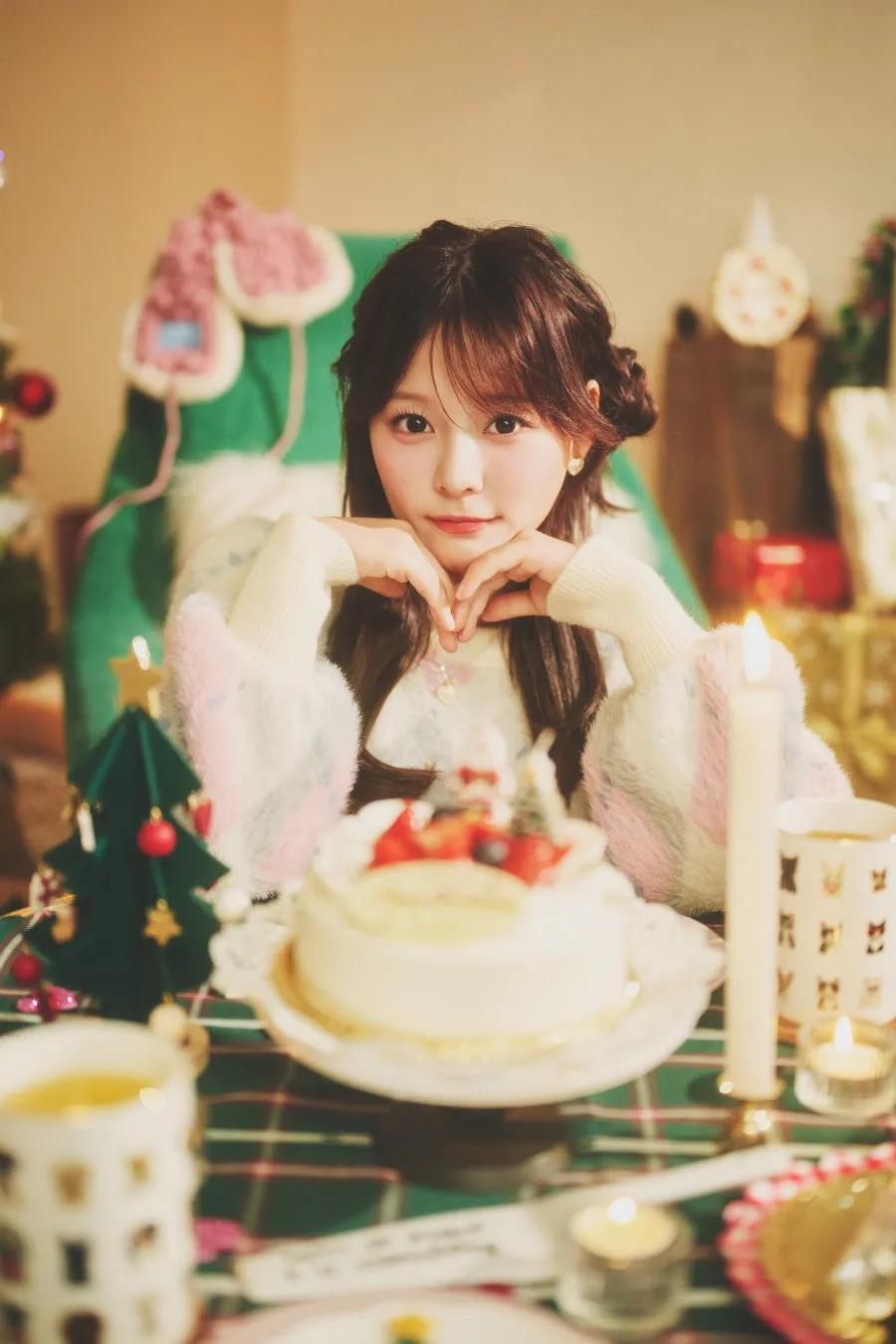 ケーキの前に座ってカメラを見つめる女性。クリスマスの雰囲気の画像