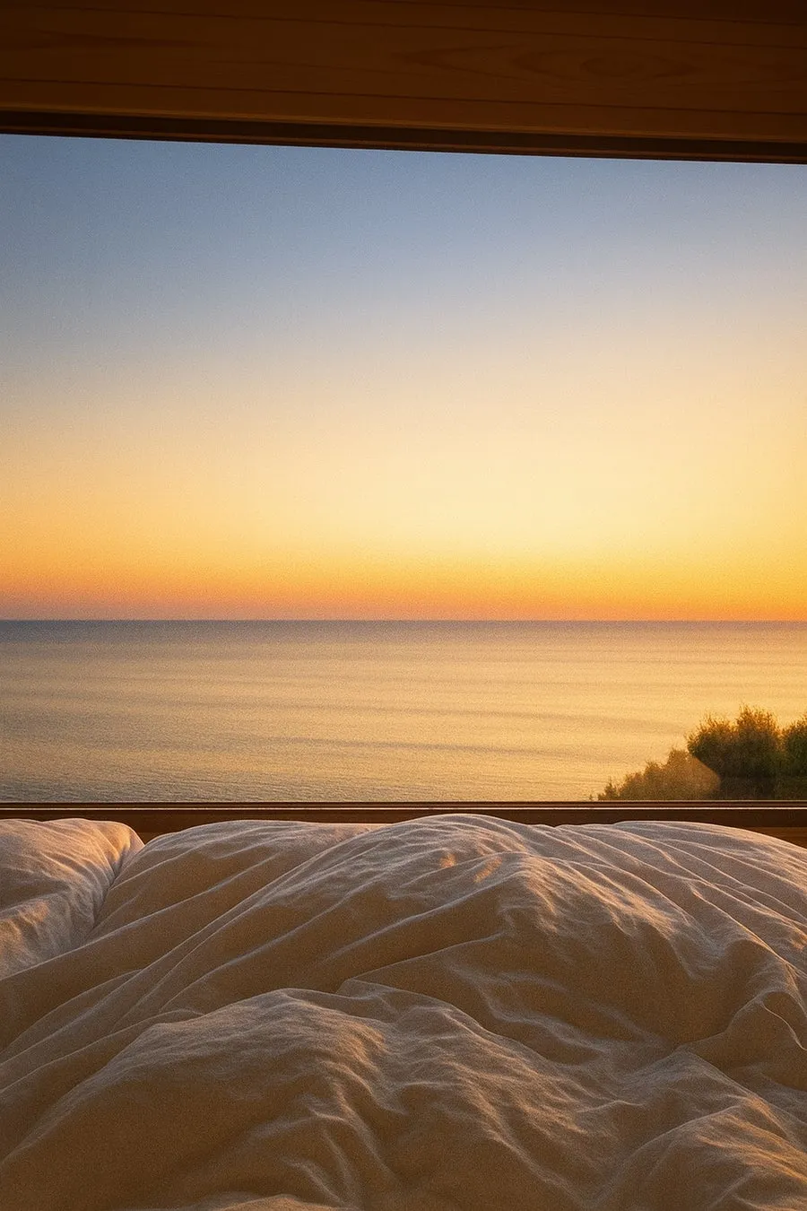 窓から見える海の夕焼けの光景。ベッドに横たわり、穏やかな夕焼けを眺めている様子。