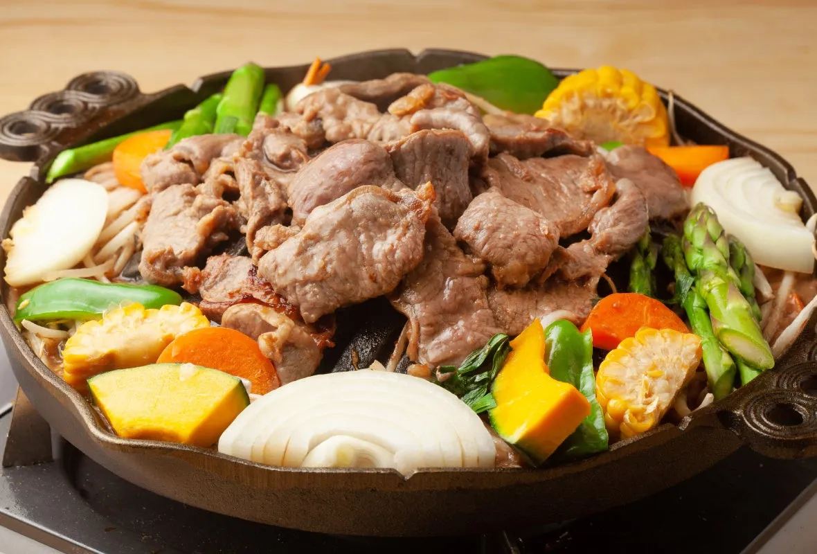 ジンギスカン鍋で調理された料理の写真です。ラム肉と野菜が美味しそうに調理されています。