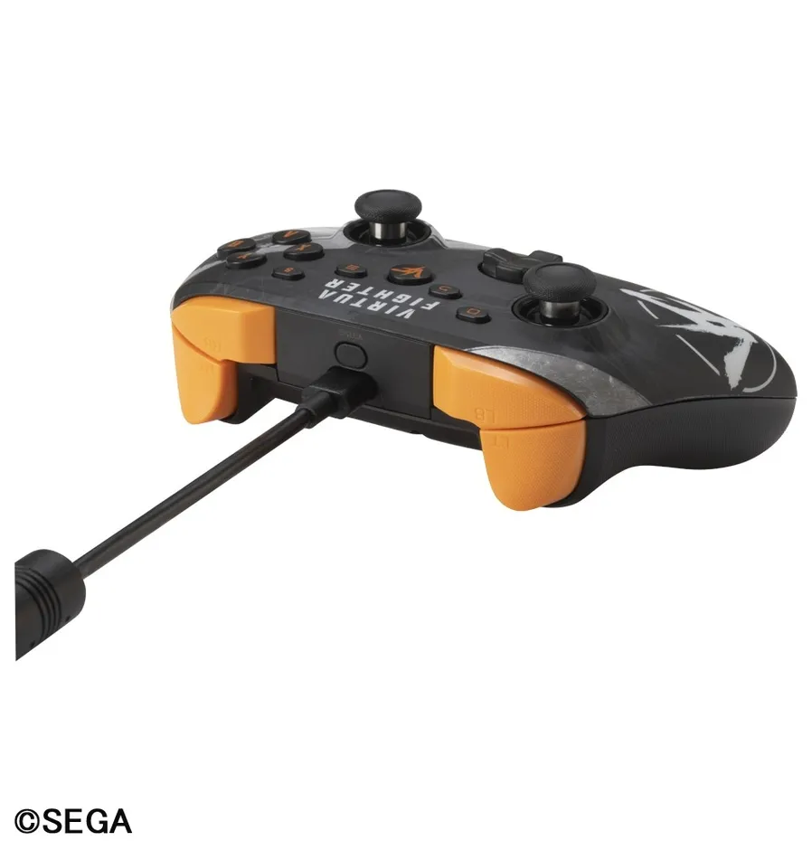 Virtua Fighterのコントローラーの画像です。コントローラーは黒色を基調とし、オレンジ色のアクセントが施されています。コントローラーにはケーブルが接続されており、SEGAのロゴが見えます。