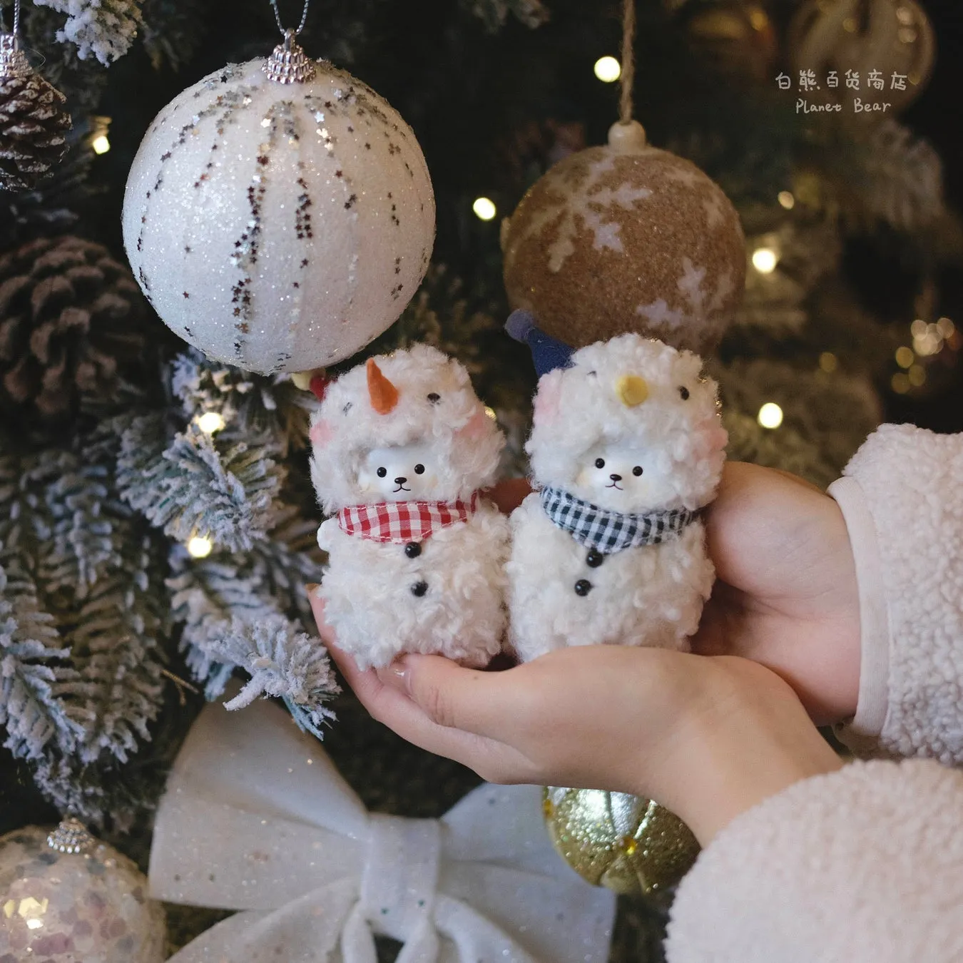 クリスマスオーナメントと雪だるまのぬいぐるみが飾られた、冬の雰囲気漂う写真。手には雪だるまのぬいぐるみが2つ抱えられている。