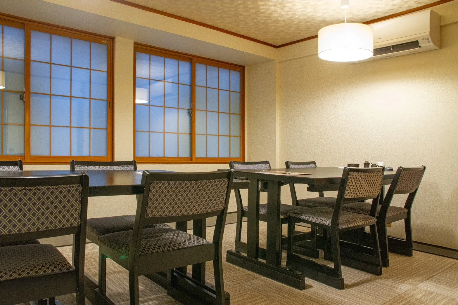 テーブルと椅子が配置された和風の部屋の画像です。窓から光が差し込み、落ち着いた雰囲気です。