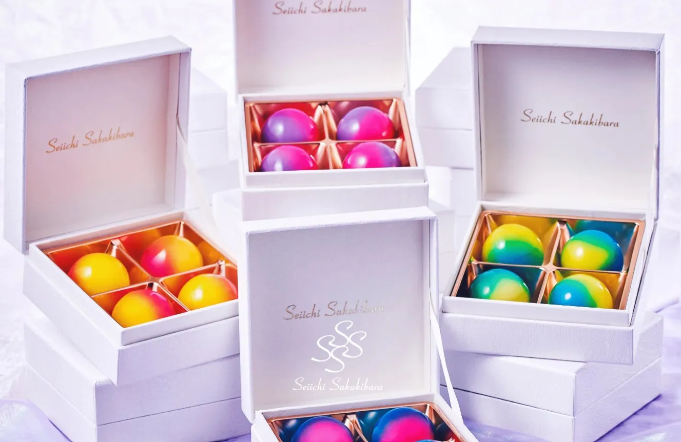 Seiichi Sakakibaraのチョコレートが詰められた白い箱が複数写っている写真。チョコレートはカラフルで、箱の中は金色の枠で区切られている。