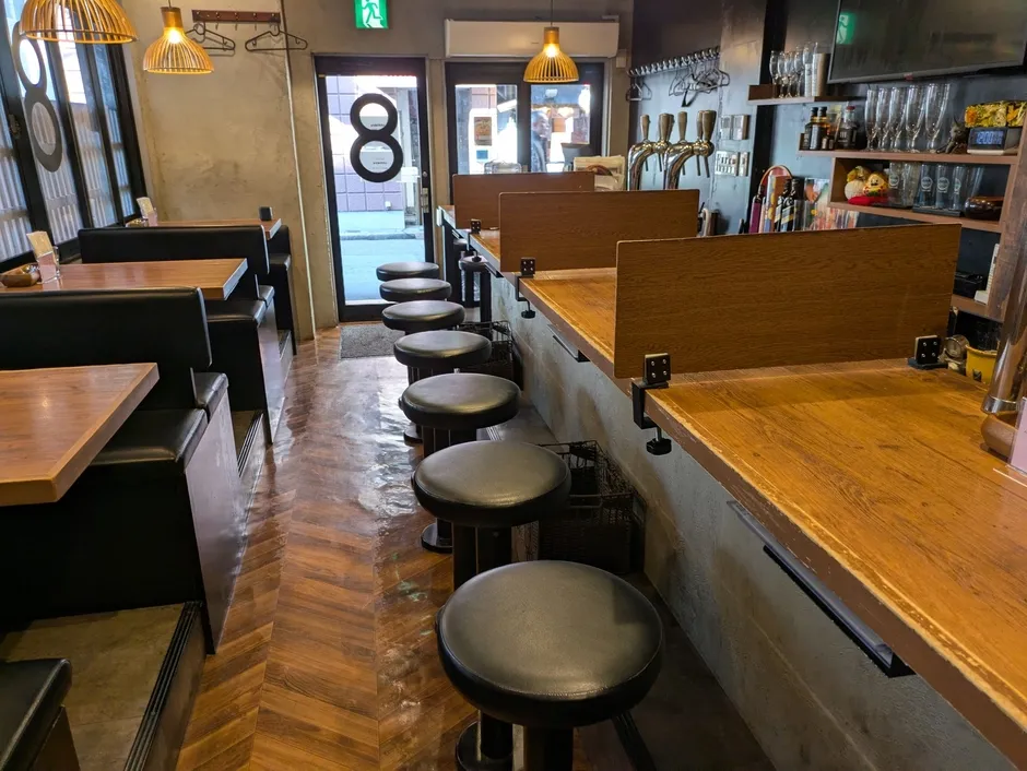 バーカウンターとテーブル席のある飲食店の内観です。