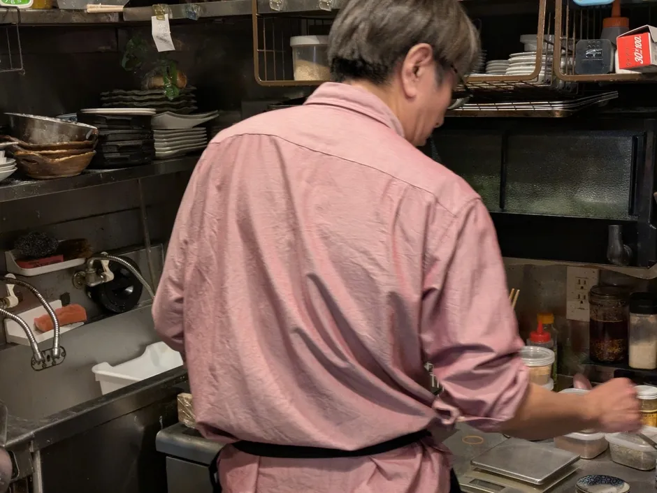 料理人がキッチンで作業している様子を捉えた写真です。