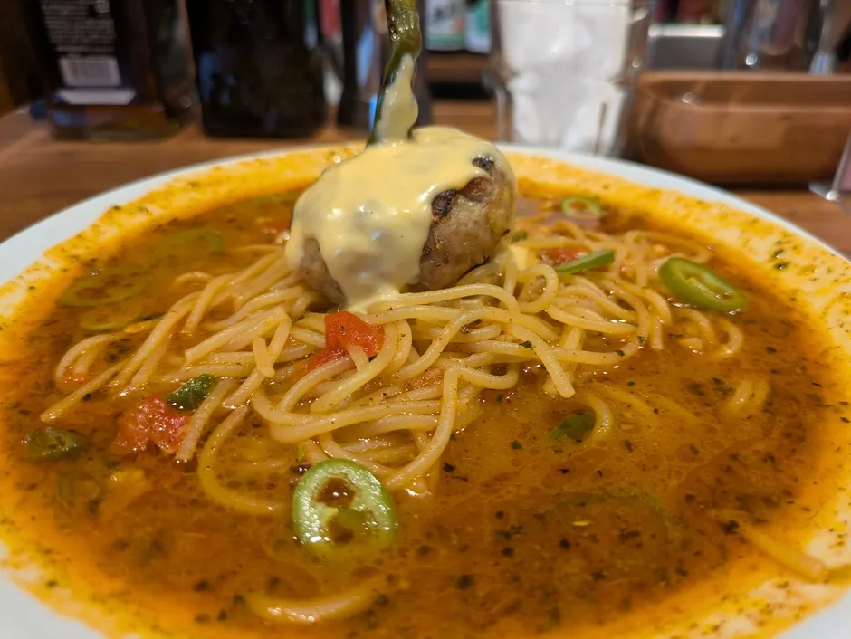チーズのかかったハンバーグが乗った、トマトソースベースのスープパスタ