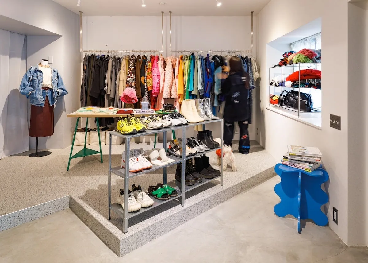 店内には、洋服や靴、小物が並べられており、洋服を選んでいる人がいる。マネキンにはデニムジャケットとスカートが飾られている。