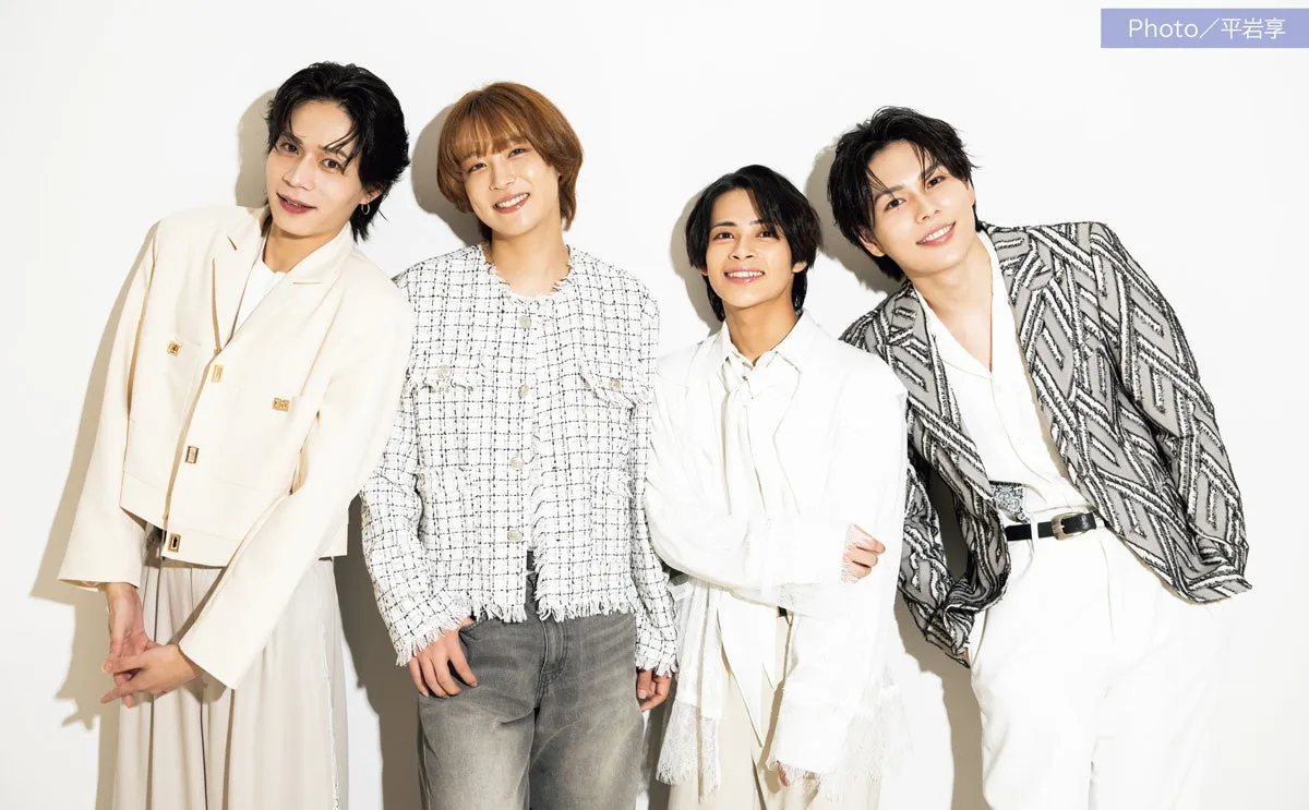 4人の男性が白い背景の前でポーズをとっています。彼らはそれぞれ異なるスタイルのジャケットを着ており、全員が笑顔でカメラを見ています。