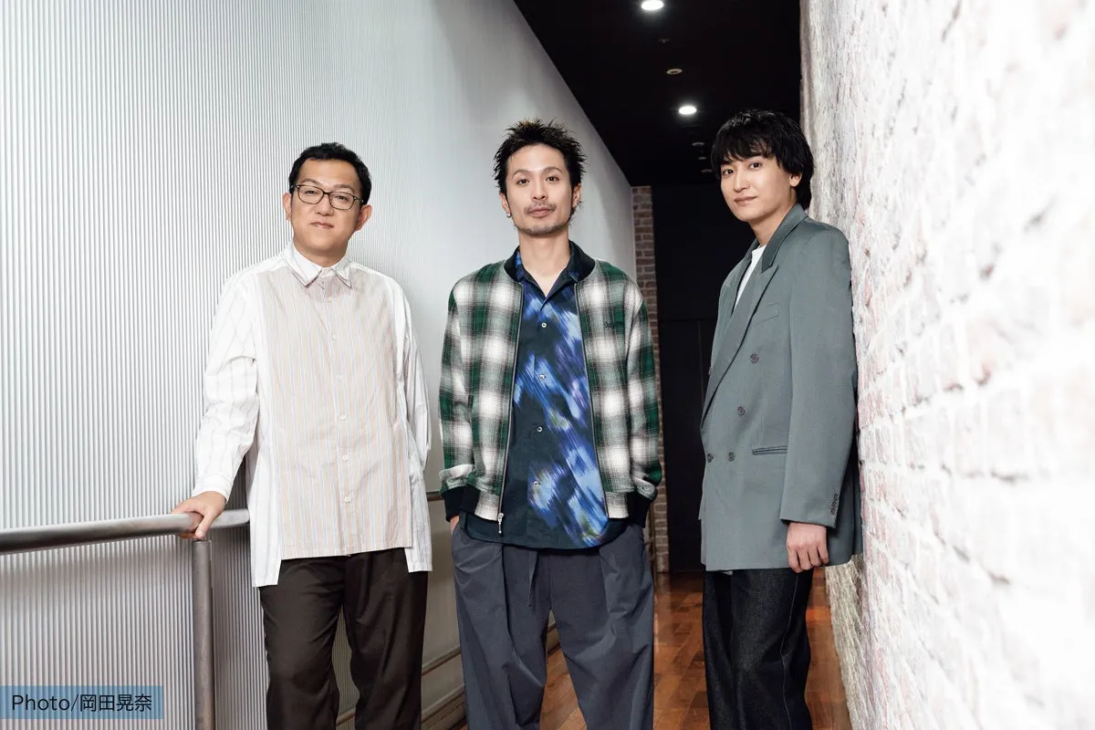 3人の男性が壁を背景に立ってポーズをとっている写真です。