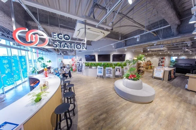 ECO STATIONという看板のある、バーカウンターやテーブル、植物が置かれたおしゃれな内装の店舗の様子。