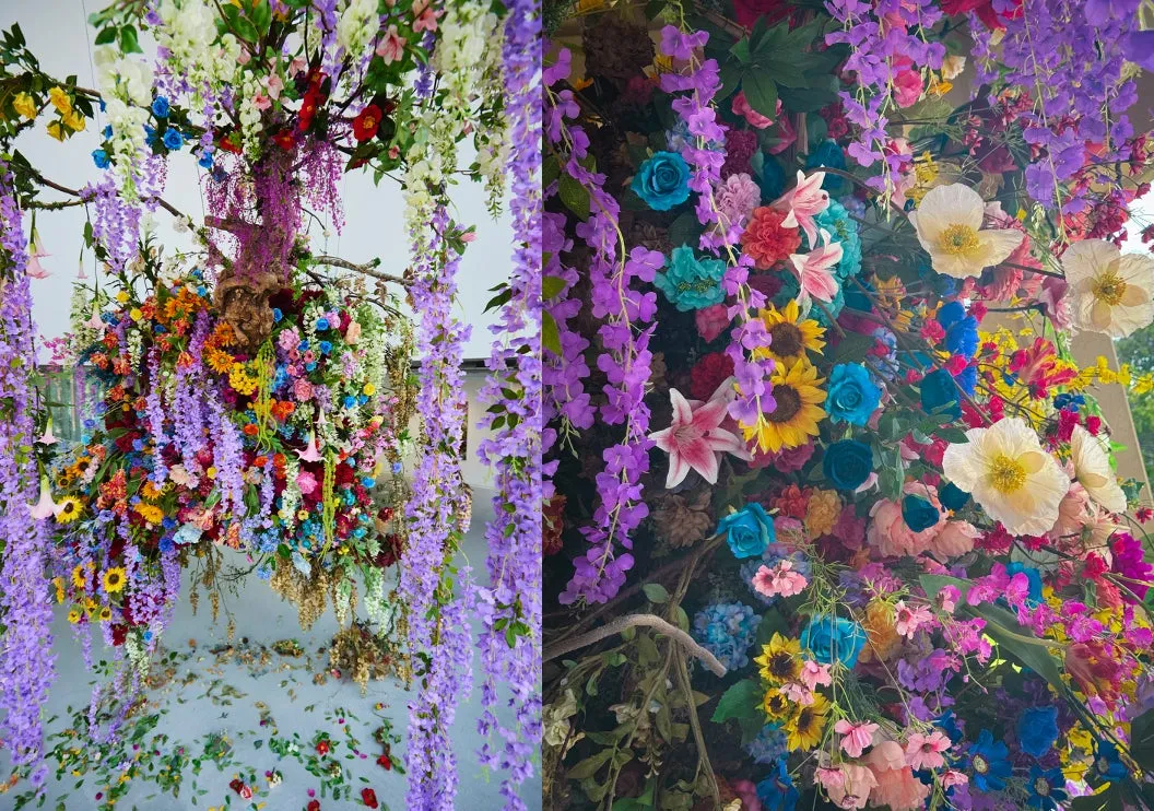色とりどりの花々で飾られた壮大なインスタレーション。紫色の藤の花が滝のように流れ落ち、様々な色の花々が密集して芸術的な空間を作り出している。