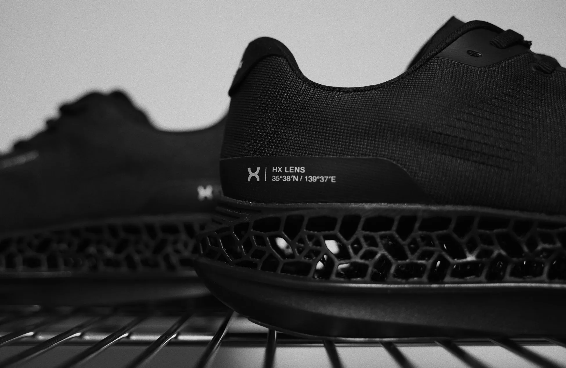 黒いランニングシューズのクローズアップ写真。シューズは、通気性のある底と、"HX LENS"と書かれたラベルが付いている。