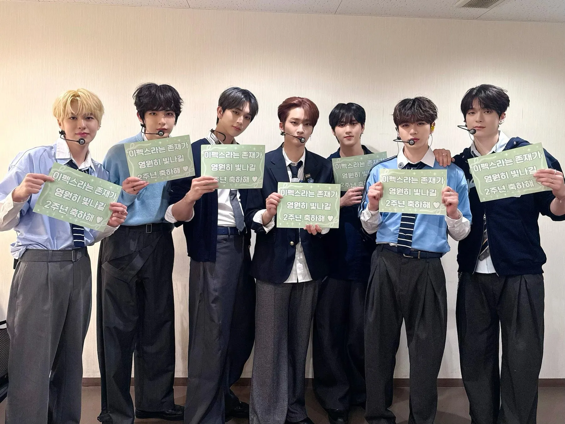 「イペックスという存在が永遠に輝きますように。2周年おめでとう」と書かれたメッセージを持つEPEXのメンバーたち。