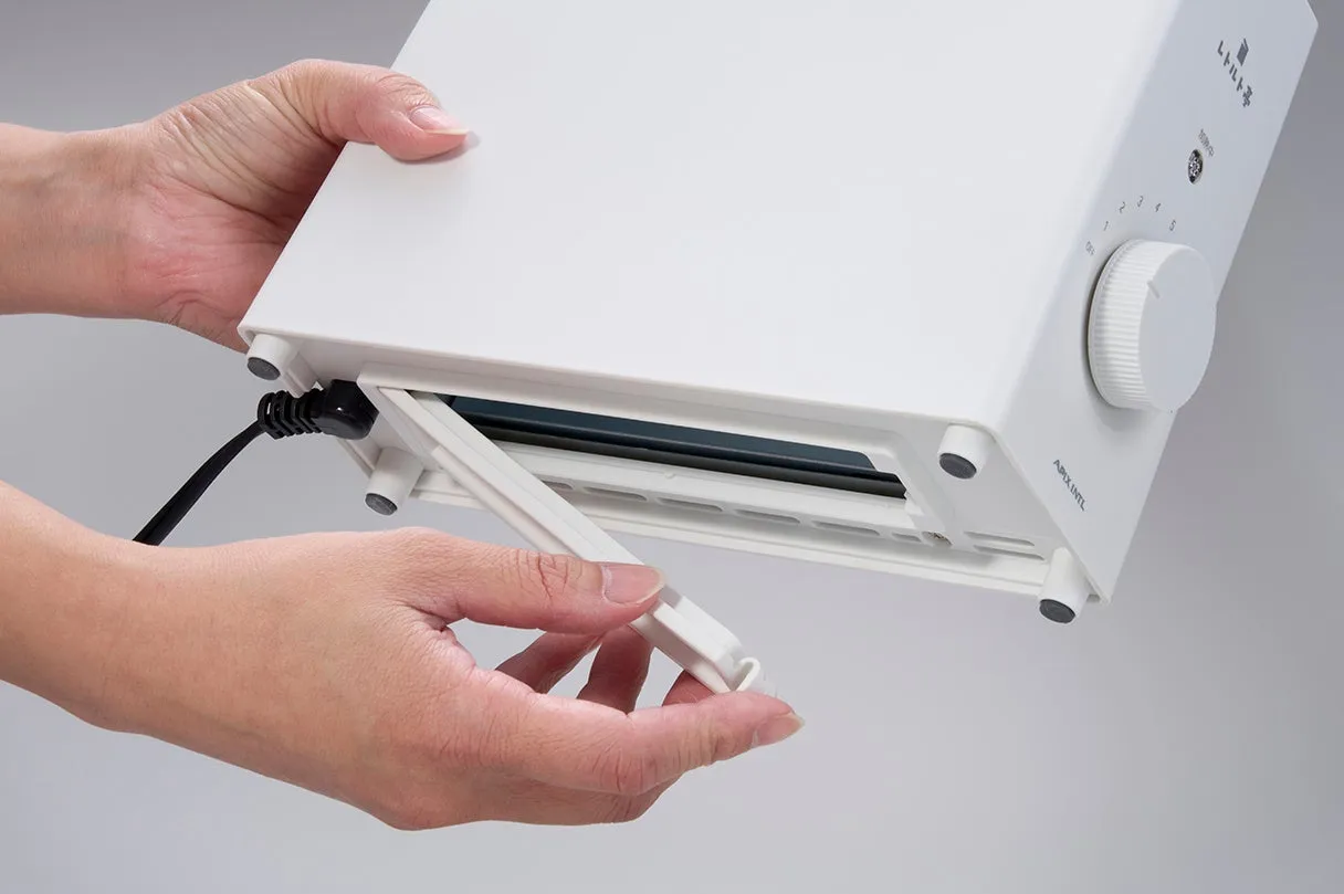 白いトースターの底面から、トレイを引き出そうとしている様子。