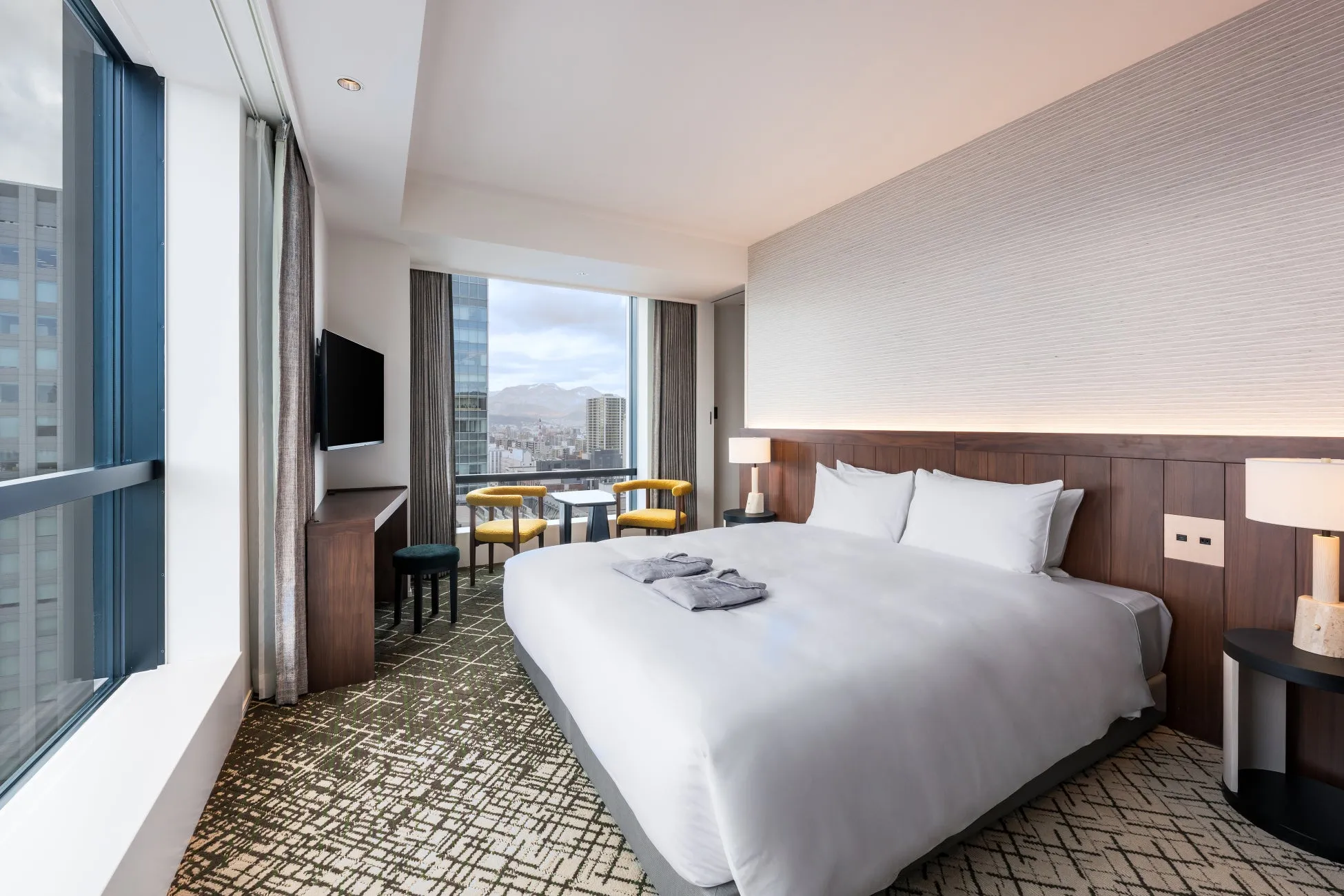 ホテルの一室。大きな窓から景色が見え、ベッド、テーブル、椅子が配置されている。