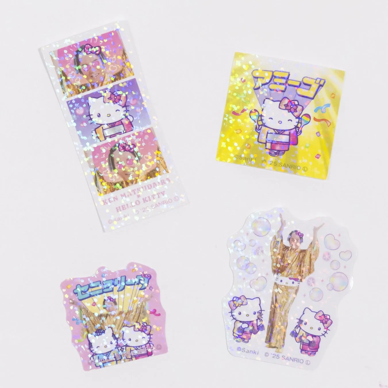 キティちゃんのステッカーが4枚並んだ写真です。写真には、松平健さんとハローキティがコラボしたデザインが写っています。キラキラした光沢のある素材で、それぞれのステッカーには様々なポーズのキティちゃんと松平健さんの姿が描かれています。