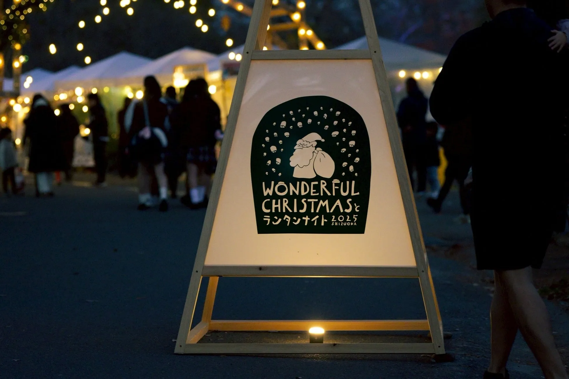 クリスマスのイベントの看板と、人が集まっている様子が写された写真です。