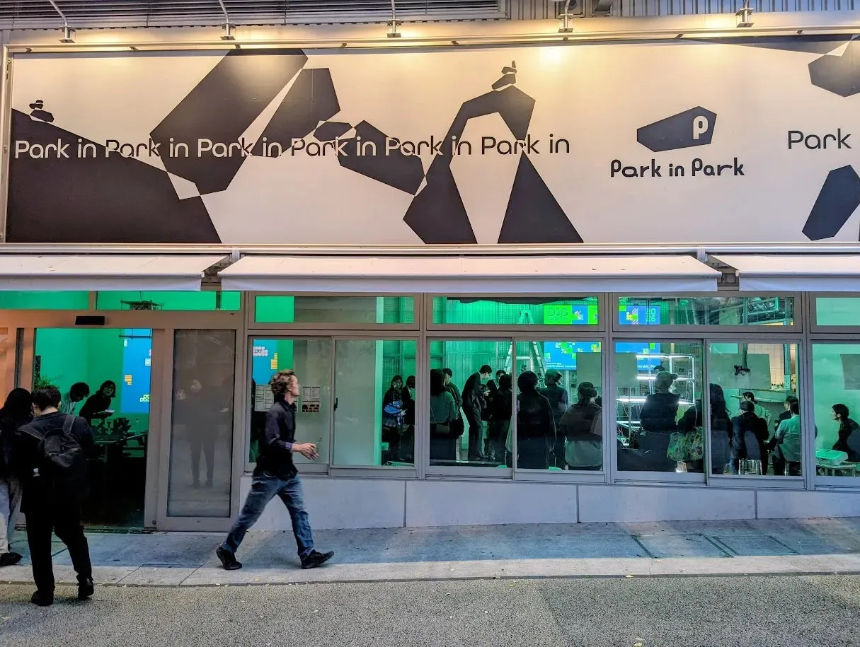 看板には「Park in Park」と書かれており、ガラス張りの店舗には多くの人が集まっている様子が写っています。歩道を歩く人もいます。