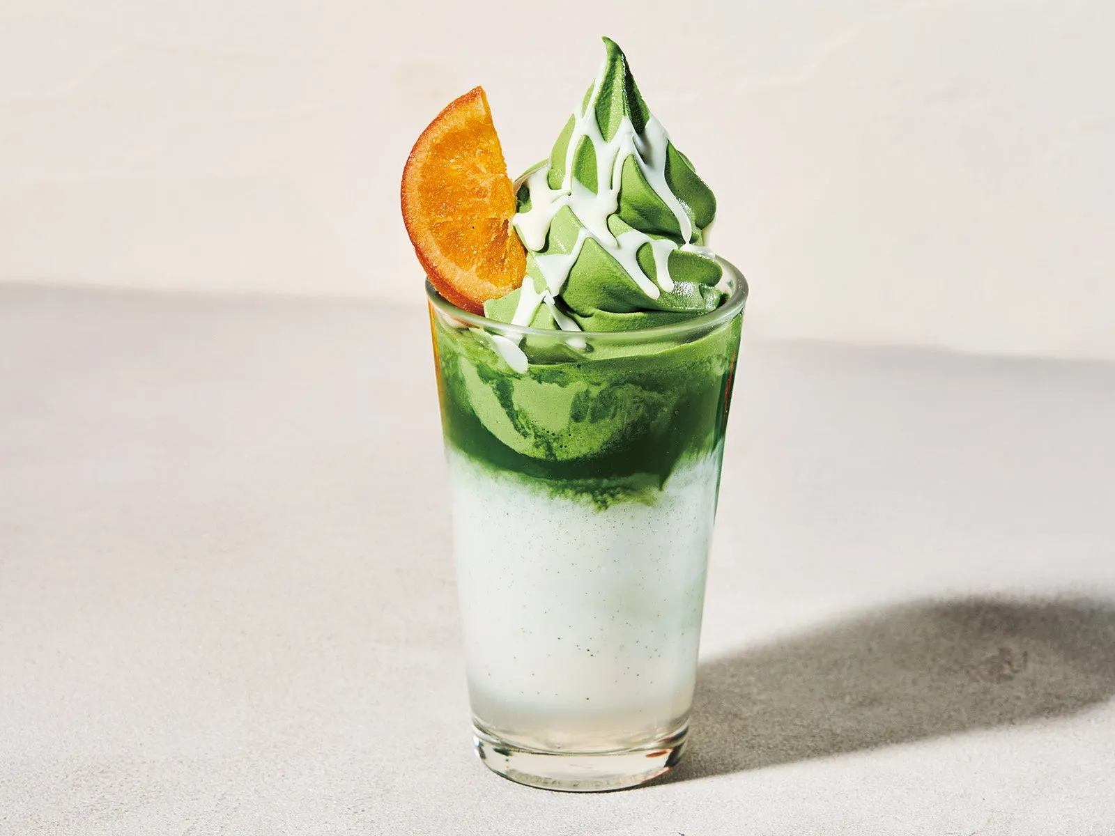 抹茶ベースの飲み物にオレンジが添えられた写真